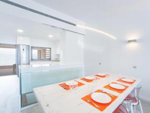 a white kitchen with a table with plates and glasses at Aixa - House In Marina Manresa Free Wifi in Alcudia