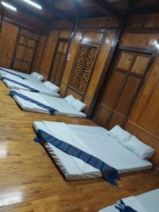 a row of beds in a room with wooden walls at Tom's House in Hòa Bình