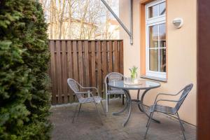 eine Terrasse mit einem Tisch und Stühlen neben einem Zaun in der Unterkunft Haus Finja in Kühlungsborn