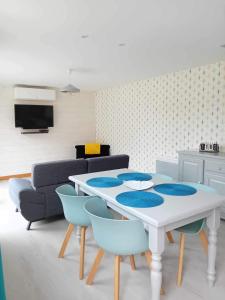 Ô Cosy في Longvilliers: غرفة معيشة مع طاولة بيضاء وكراسي زرقاء