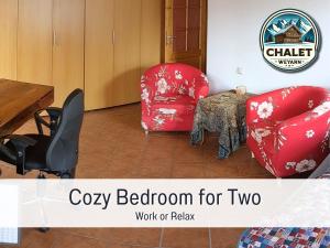 Habitación con 2 sillas rojas y mesa. en Chalet Weyarn: Doppelzimmer mit Balkon, en Weyarn