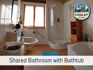 een badkamer met een gedeelde badkamer met een bad en een wastafel bij Chalet Weyarn: Doppelzimmer mit Balkon in Weyarn