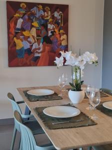 una mesa con platos y copas de vino y una pintura en Vai Lodge - Vue imprenable sur le lagon ! en Punaauia