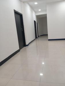 an empty hallway with white walls and black doors at ALPHA Hotel in Imphal