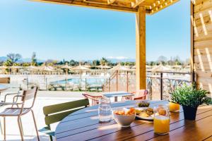 - une table en bois avec une assiette de nourriture sur la terrasse dans l'établissement Résidence Pierre & Vacances Premium Domaine du Golfe du Lion, à Saint-Cyprien
