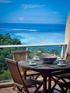 una mesa en un balcón con vistas al océano en Vai Lodge - Vue imprenable sur le lagon ! en Punaauia
