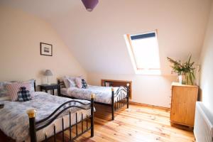 1 dormitorio en el ático con 2 camas y ventana en *Spacious Irish Cottage*, en Fanore