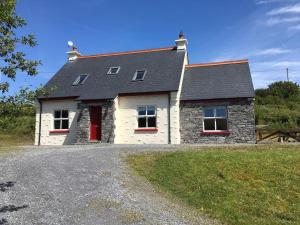 ein Haus mit einer roten Tür auf einer Kieseinfahrt in der Unterkunft *Spacious Irish Cottage* in Fanore