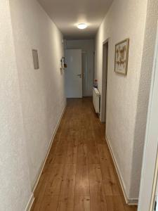 un pasillo vacío con suelo de madera dura y paredes blancas en Appartement Cormondrèche, en Neuchâtel