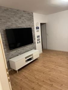 een woonkamer met een flatscreen-tv op een bakstenen muur bij Appartement Cormondrèche in Neuchâtel