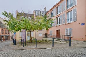 a tree in the middle of a street next to a building at Welcome to Forest House in Marly-le-Roi