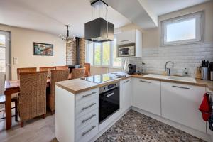 a kitchen with white cabinets and a dining room at La Grange des Ours - Proche de la plage in Bernières-sur-Mer