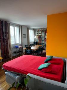 a bedroom with a red bed and a dining room at Bel appartement J.O. 2024 proche sites olympiques in Boulogne-Billancourt