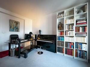 a room with a desk and a piano in a book shelf at Bel appartement J.O. 2024 proche sites olympiques in Boulogne-Billancourt