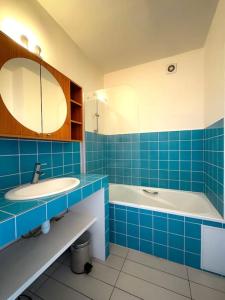 a blue tiled bathroom with a sink and a tub at Bel appartement J.O. 2024 proche sites olympiques in Boulogne-Billancourt