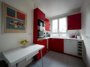 a kitchen with red cabinets and a white counter top at Bel appartement J.O. 2024 proche sites olympiques in Boulogne-Billancourt