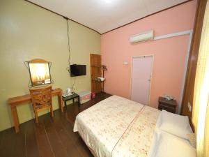a bedroom with a bed and a table and a mirror at OYO 90968 Teratak Samuderakita, Chalet & Guesthouse in Kampong Gong Badak