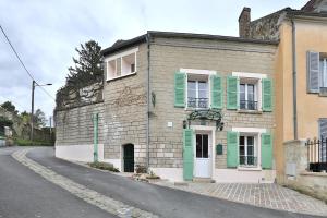 un antiguo edificio de ladrillo con persianas verdes en una calle en L'ESTAMPE, en Auvers-sur-Oise