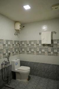 a bathroom with a toilet and towels on the wall at GRANDE IVORY INN in Kalpetta