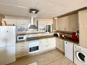 a kitchen with a white refrigerator and a dishwasher at Seafront apartment in La Garrofa near the beach in La Garrofa