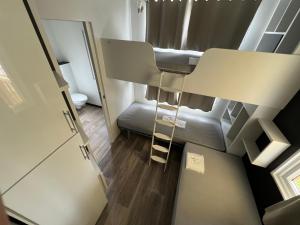 Habitación pequeña con sofá y escalera en MobilHome Comfort XL (37m2) : 2 Chambres (6 personnes) - 2 SDB - Clim centralisée - TV - Terrasse balcon, en Cadenet