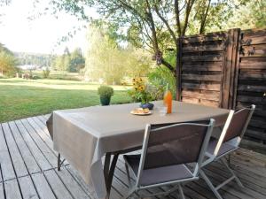 a table and chairs on a wooden deck with a garden at Holiday Home in Auvergne with Roofed Garden and Terrace in Calvinet