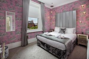 Un dormitorio con papel pintado de color rosa y una cama con animales de peluche. en Breck Apartments, en Poulton le Fylde