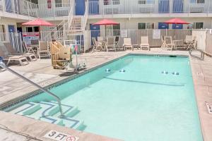 una piscina en un hotel con sillas y sombrillas en Motel 6-Lancaster, CA, en Lancaster