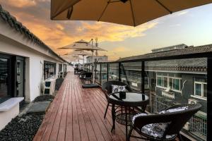 a balcony with chairs and tables and an umbrella at Shisandufu Youth Hostel in Xi'an