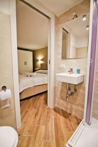 uma casa de banho com um lavatório, um espelho e uma cama em La casa di anna em Nápoles