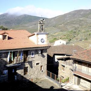 a building with a clock tower with mountains in the background at Casa Rural La Ortiga in Robledillo de Gata