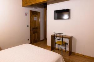 a bedroom with a bed and a desk and a television at Posada Villa Matilde in Cillorigo de Liebana