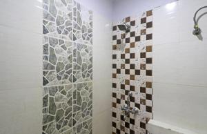 ein Bad mit einer Dusche und einer Mosaikfliesenwand in der Unterkunft Hotel Samara Kingdom Near Delhi Airport in Neu-Delhi