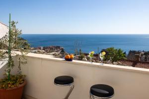 a balcony with three stools on a ledge with the ocean at Charming view old town ap, with free parking in Dubrovnik