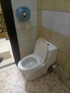 a white toilet in a bathroom with a toilet paper dispenser at Oasis Hotel and Guest House. Voi in Voi