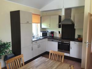 a kitchen with white cabinets and a table and chairs at Detached bungalow with dishwasher in a green area in Kopp