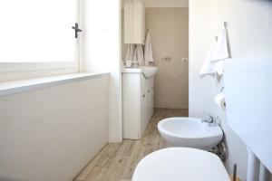 a white bathroom with a toilet and a sink at La Casa dei Laghi 1 Comabbio Monate Maggiore Orta in Mercallo
