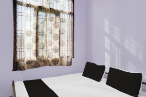 Pokój z łóżkiem i oknem z zasłonami w obiekcie OYO Flagship Aravali Guest House & Restaurant w Kishangarh