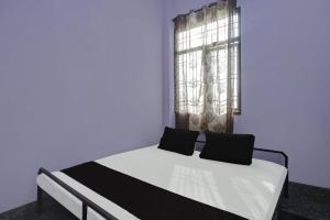 Cama en habitación azul con ventana en OYO Flagship Aravali Guest House & Restaurant, en Kishangarh