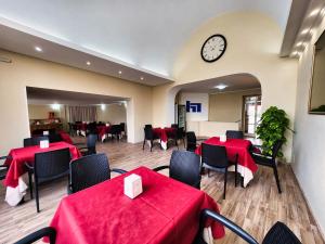 ボルセーナにあるHotel Nazionaleの赤いテーブルと椅子、時計のあるレストラン