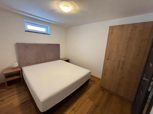 1 dormitorio pequeño con 1 cama y armario de madera en Our's Living, en Hollersbach im Pinzgau