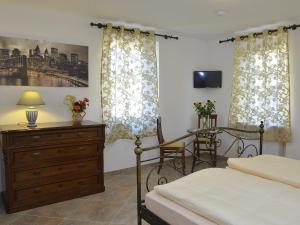 Schlafzimmer mit einem Bett, einer Kommode und Vorhängen in der Unterkunft Hotel Restaurant La Corona in Maikammer