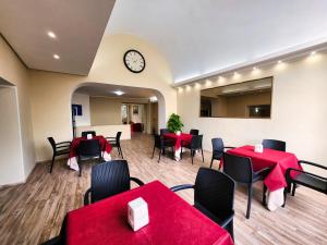 a restaurant with red tables and chairs and a clock at Hotel Nazionale in Bolsena