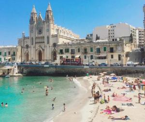 a group of people on a beach in front of a building at St Julians - Balluta Bay large 3 bedroom apartment in Sliema