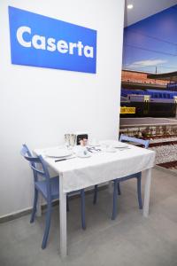 a white table with chairs and a sign with a train at B&B Smart Station Caserta in Caserta