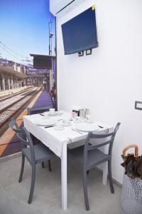 a white table with chairs and a tv on a wall at B&B Smart Station Caserta in Caserta