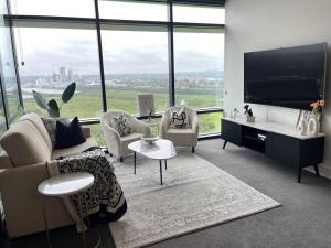 Sydney Olympic Park View Bliss Modern Design في سيدني: غرفة معيشة مع أريكة وكراسي وتلفزيون