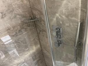 a shower stall with a glass door with a shower at Cosy Studio in Heart of London in London