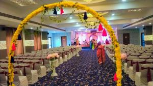 un salón de banquetes con mesas blancas y sillas blancas en Marigold Celebration hotel, en Rāipur