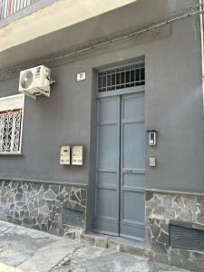 un edificio grigio con una porta e un ventilatore di Etna charme apartment a Catania